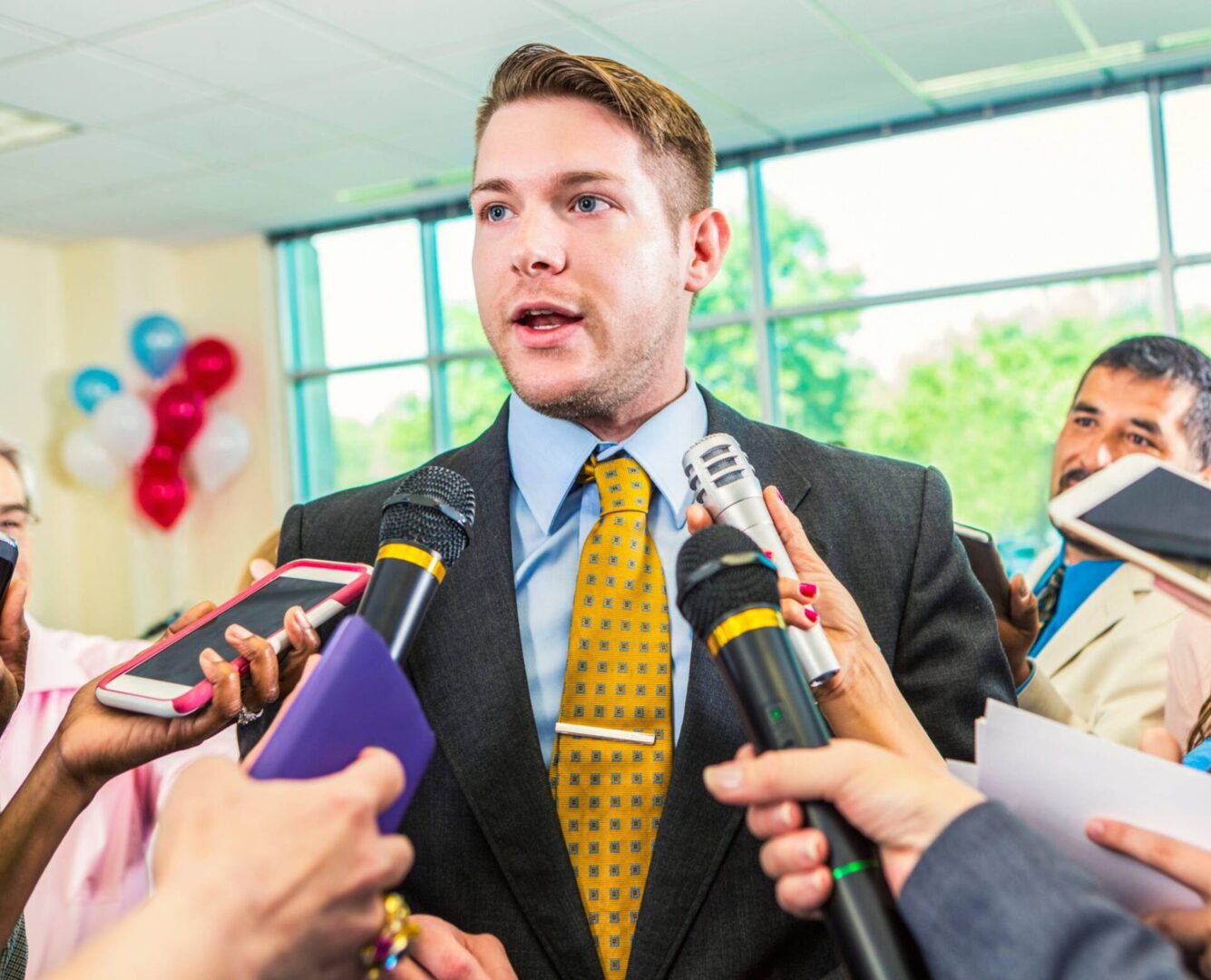 Man speaking to reporters with microphones