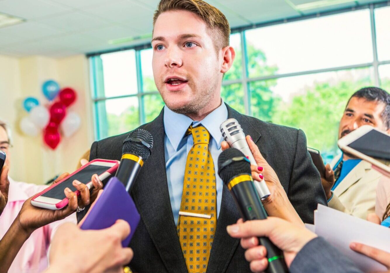 Man speaking to reporters with microphones